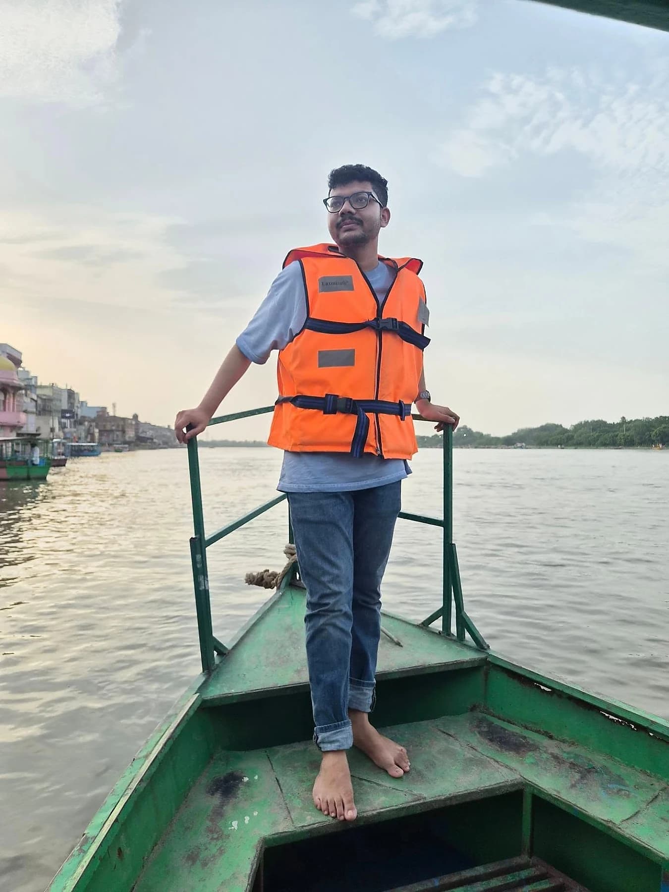 Raktim Ranjit wearing an orange life jacket on a small boat on the river