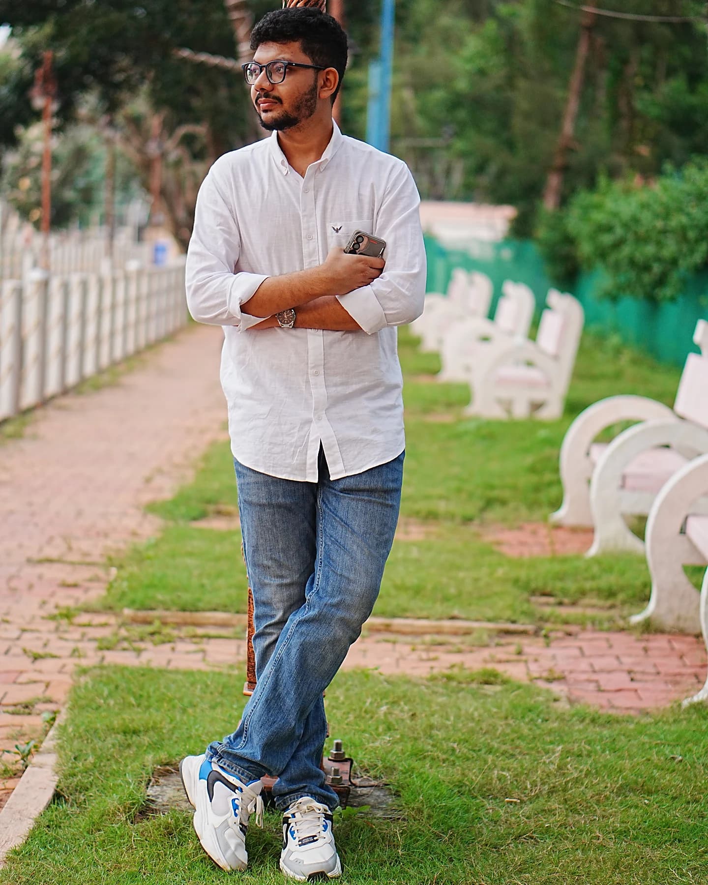 Raktim Ranjit in a white shirt and jeans, standing on a garden path