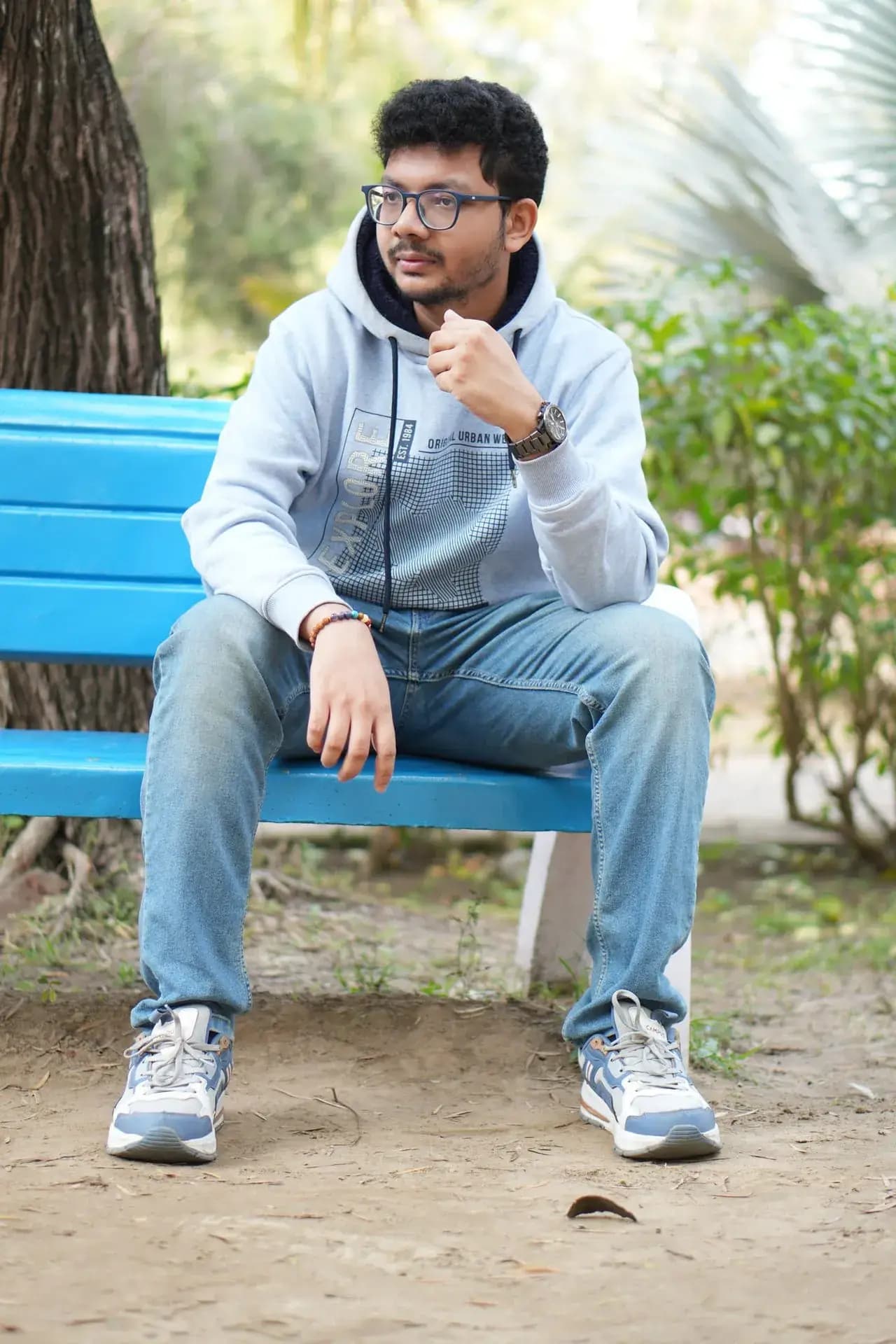 Raktim Ranjit sitting on a bright blue bench, resting his chin on his hand