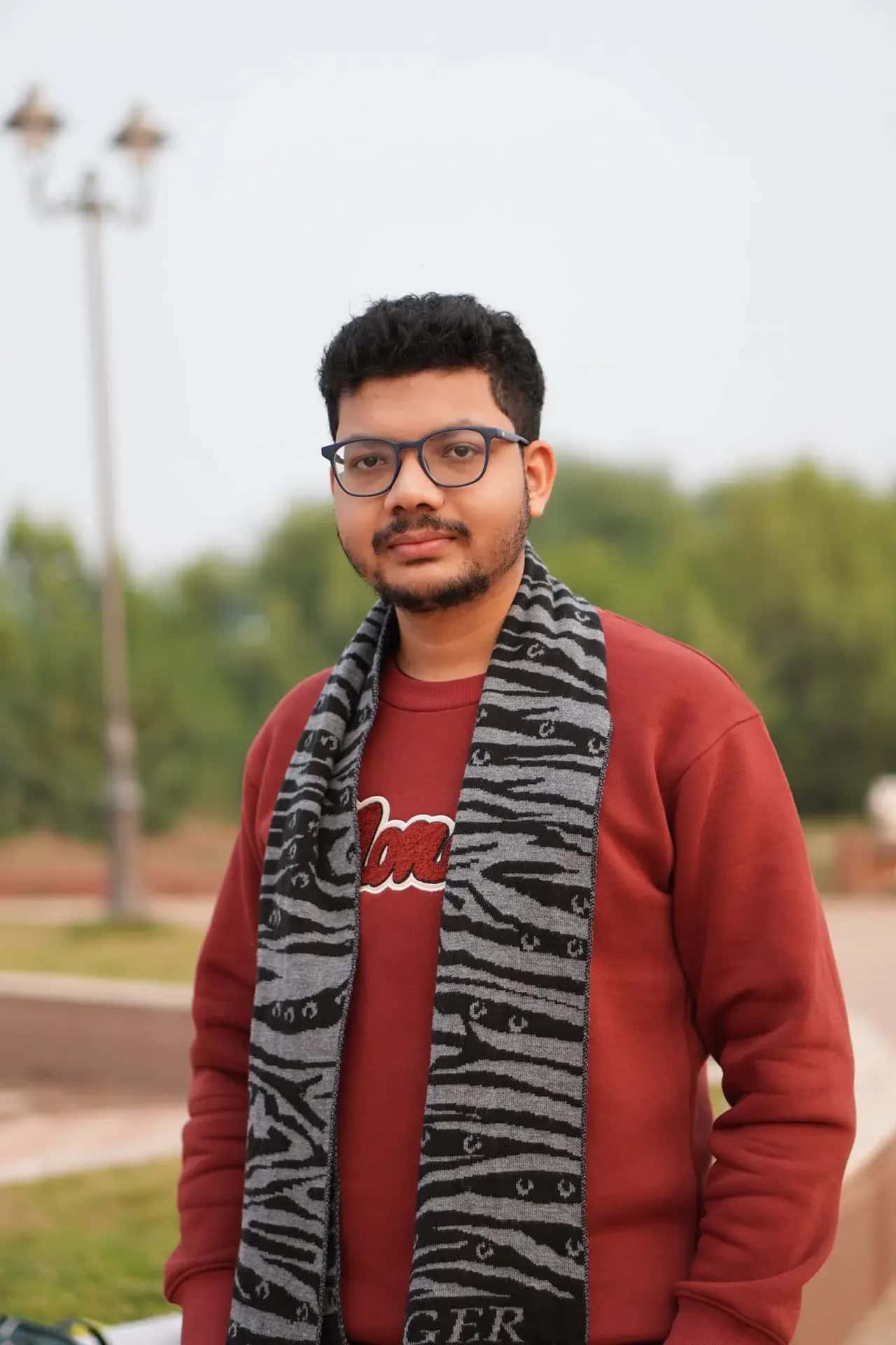 Raktim Ranjit, software engineer and founder of NodeDR Infotech, standing outdoors in a red sweater and scarf